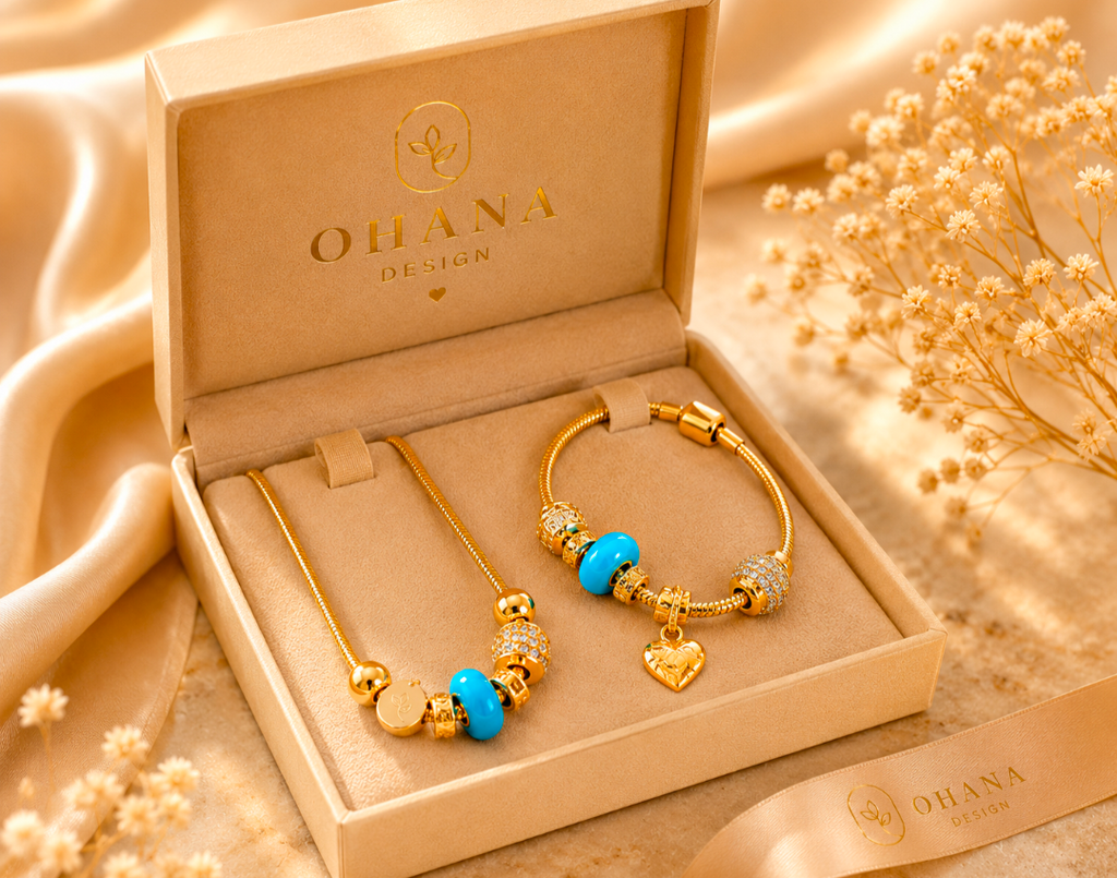 Gold jewelry set with blue accents in an open 'Ohana Design' box on a beige fabric background.