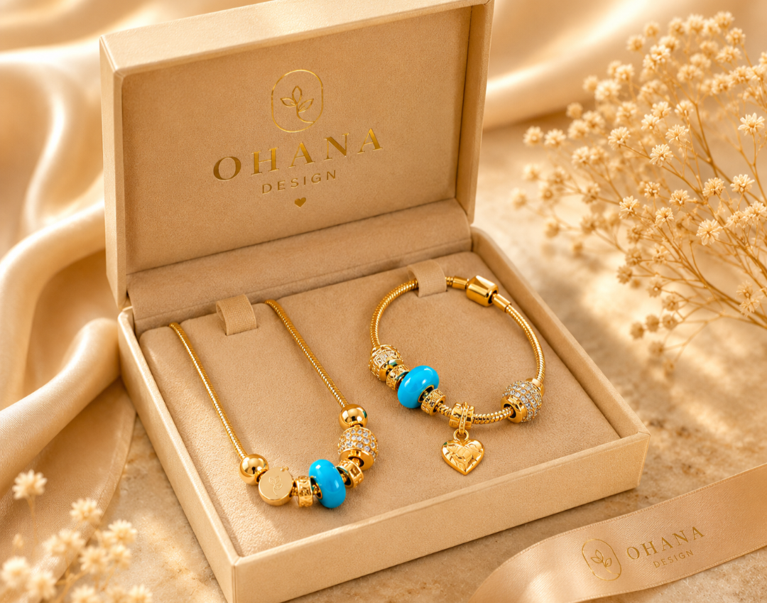 Gold jewelry set with blue accents in an open 'Ohana Design' box on a beige fabric background.